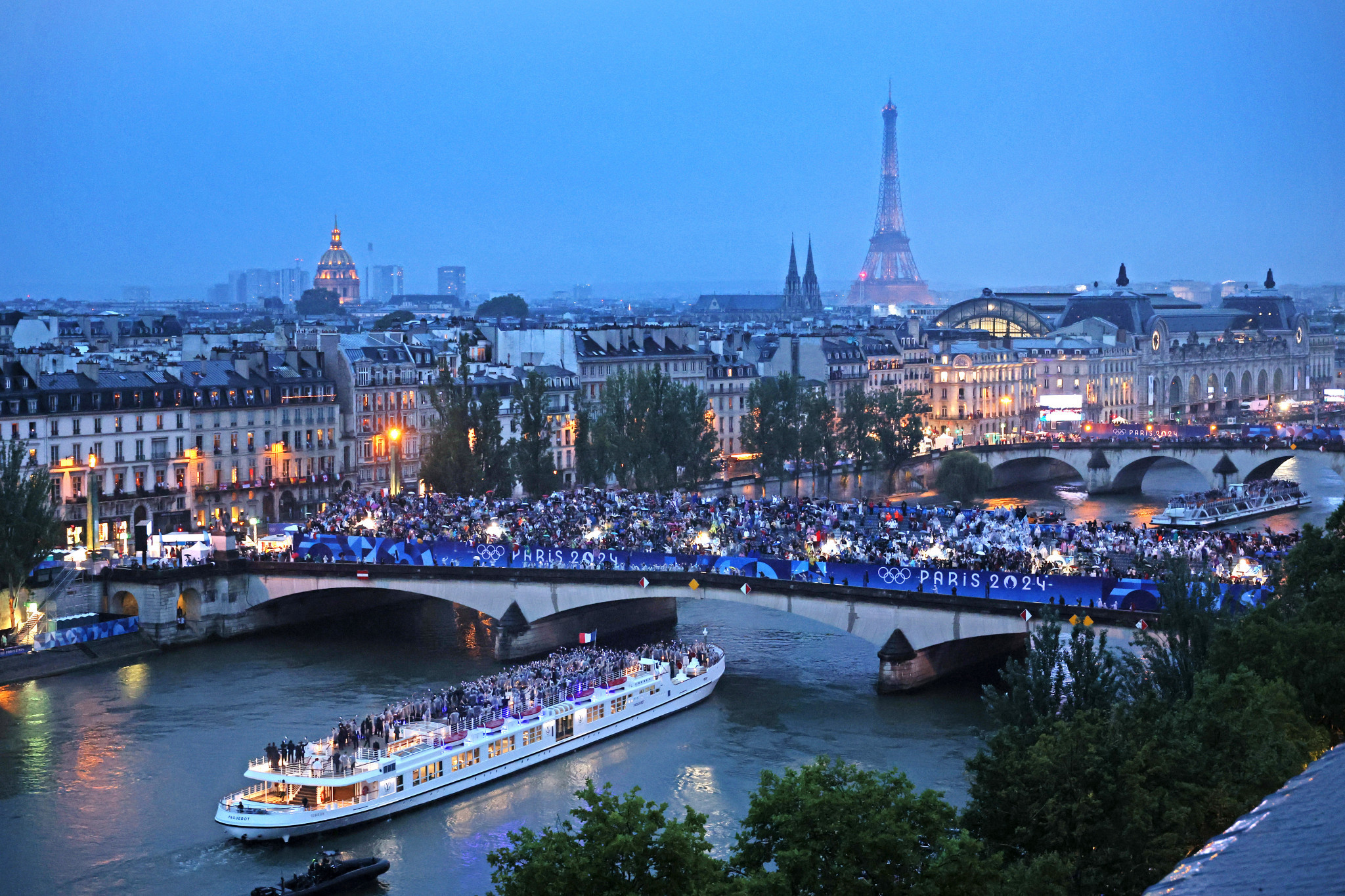 Spectators look on as athletes from Team France pass by on a boat on the River Seine during the opening ceremony of the Paris 2024 Olympic Games. GETTY IMAGES