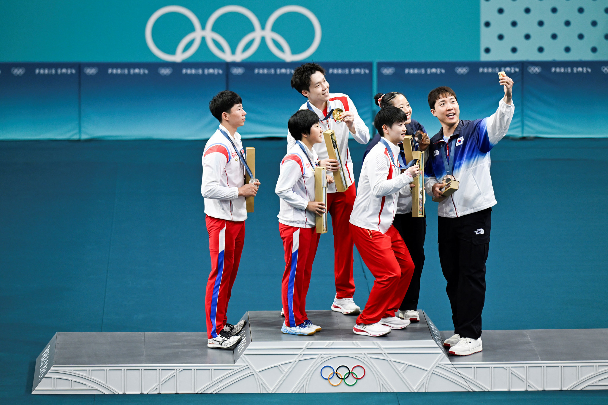 South Korea's Lim Jonghoon takes a selfie on the podium with North Korean and Chinese mixed table tennis teams at the Paris 2024 Olympic Games. GETTY IMAGES