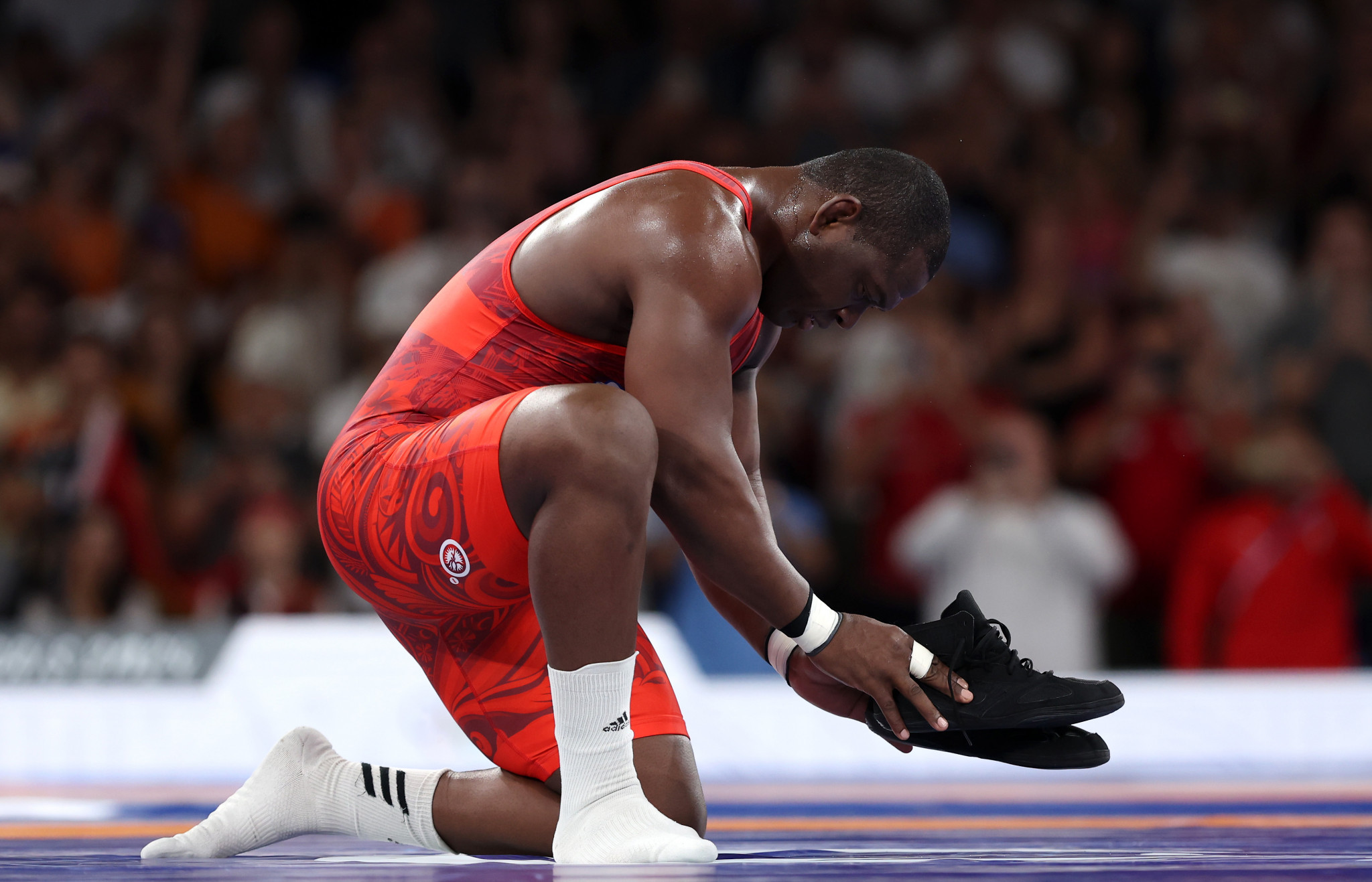 Mijain Lopez Nunez of Team Cuba removes his shoes to signify his retirement following his victory in the Wrestling Men's Greco-Roman 130kg Gold Medal match at the Paris 2024 Olympic Games. GETTY IMAGES