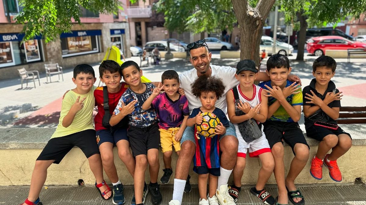 A picture of Mounir Nasraoui alongside a group of children. @hustle_hard_304 (Instagram)