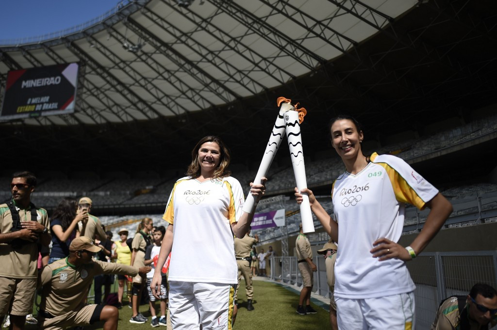 Volleyball players Ana Flavia (left) and Sheilla Castro hold the Olympic Torch as it arrives at the Mineirao Stadium in Belo Horizonte