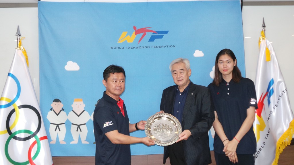 World Taekwondo Federation President Chungwon Choue, centre, poses with coach Kwak Yong-taek and Cambodian athlete Sorn Seavmey, right ©WTF