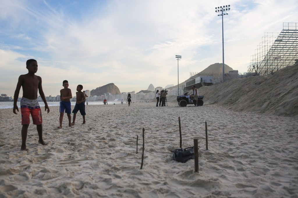Young beachgoers walk near a body part, covered in a plastic bag, which was discovered on Copacabana Beach near the Olympic beach volleyball venue ©Getty Images