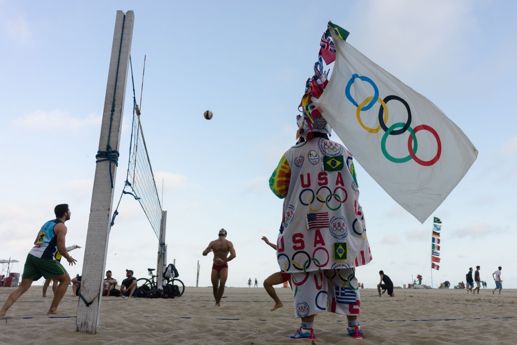 An Olympic fan in flamboyant dress watches a game of beach volleyball on Copacabana beach ©Getty Images