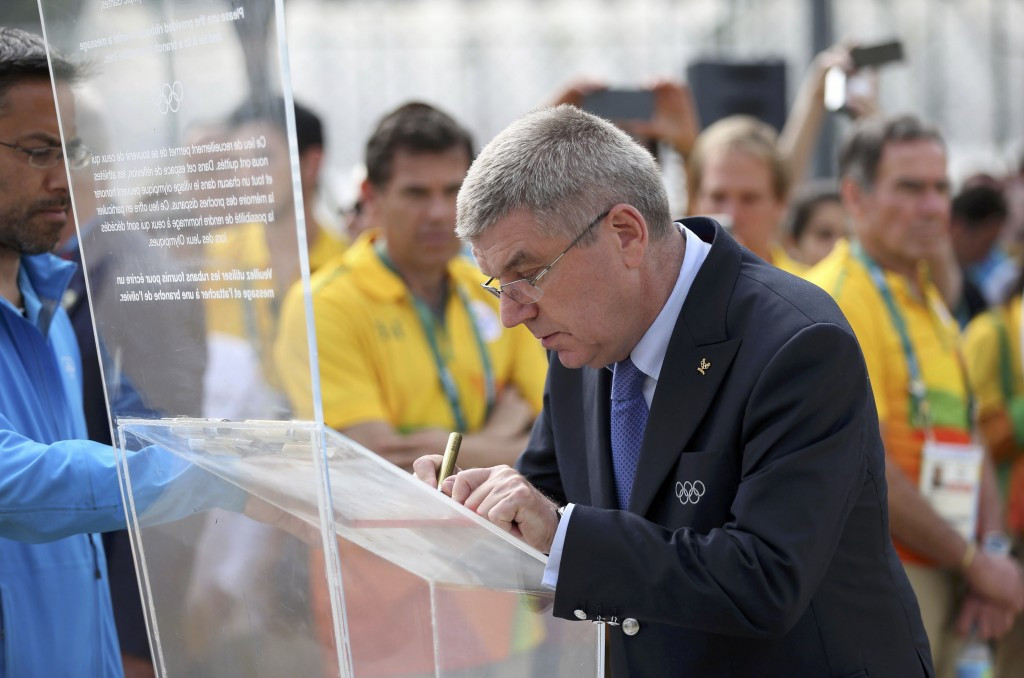 Thomas Bach signing a plaque during his visit ©Getty Images