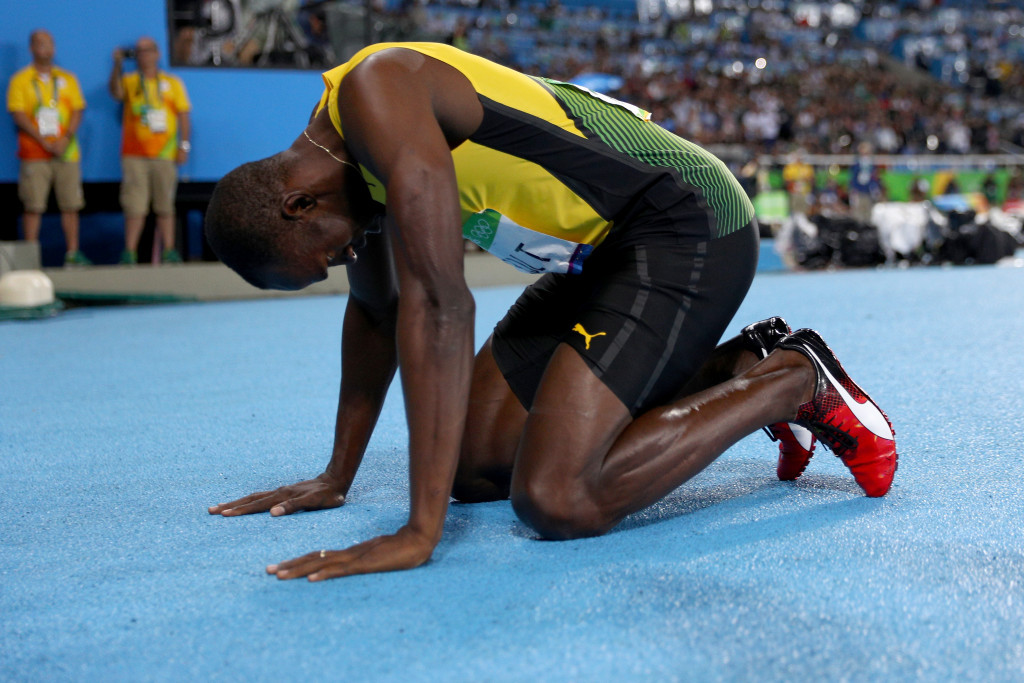 Usain Bolt sinks to the ground in celebration after a third successive Olympic 200m title ©Getty Images