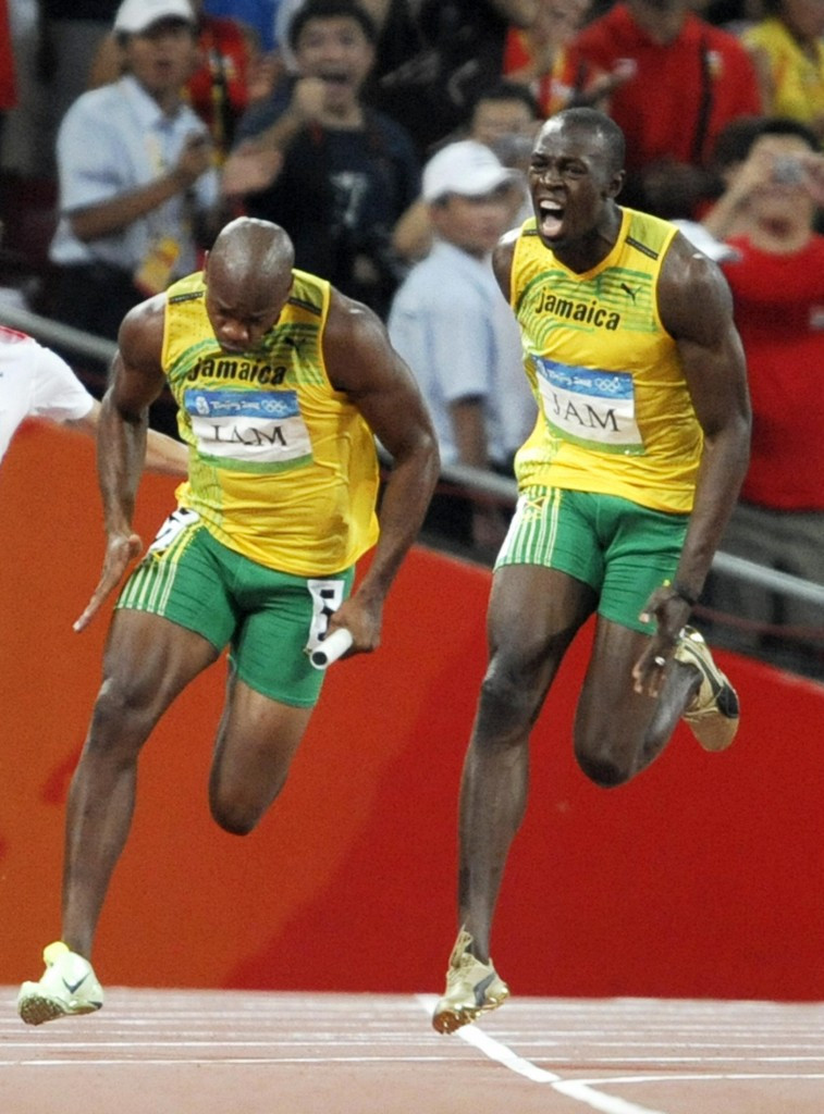 Usain Bolt urges his colleague Asafa Powell towards the line during Jamaica's 4x100m victory at the Beijing 2008 Olympics in a world record of 37.10 ©Getty Images