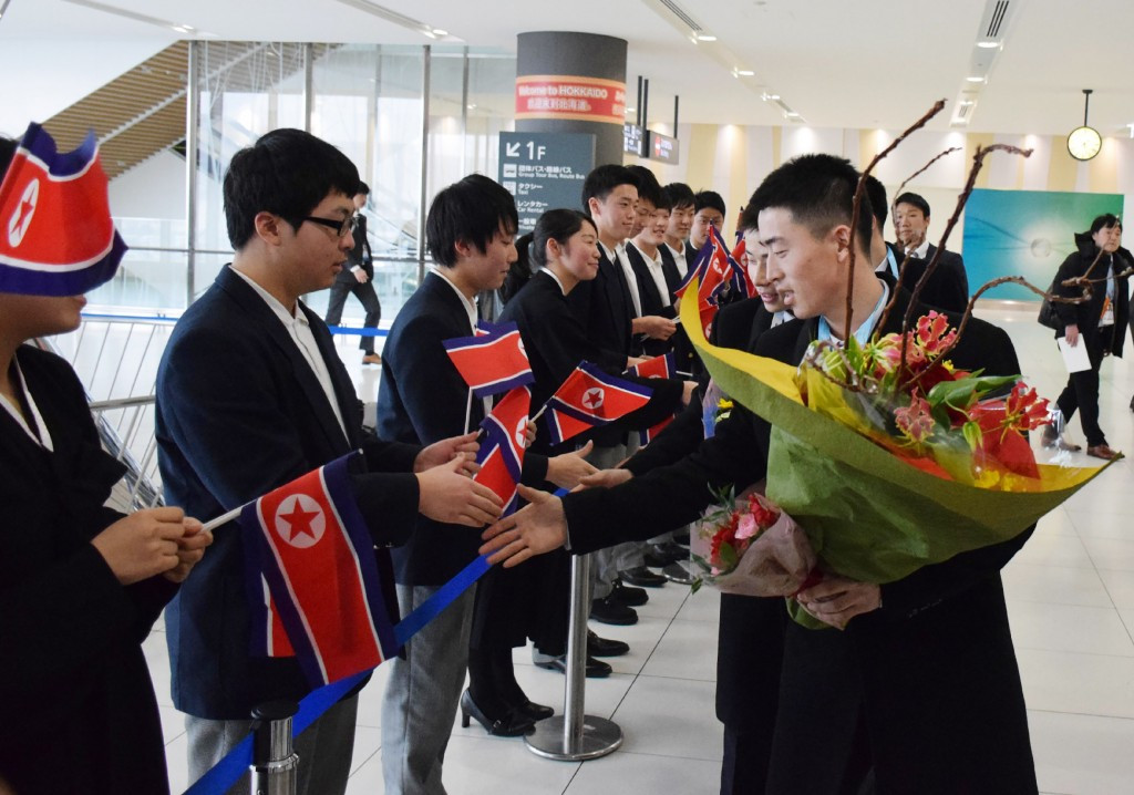 North Korean team members are greeted by flagwaving supporters on their arrival in Sapporo ©Getty Images