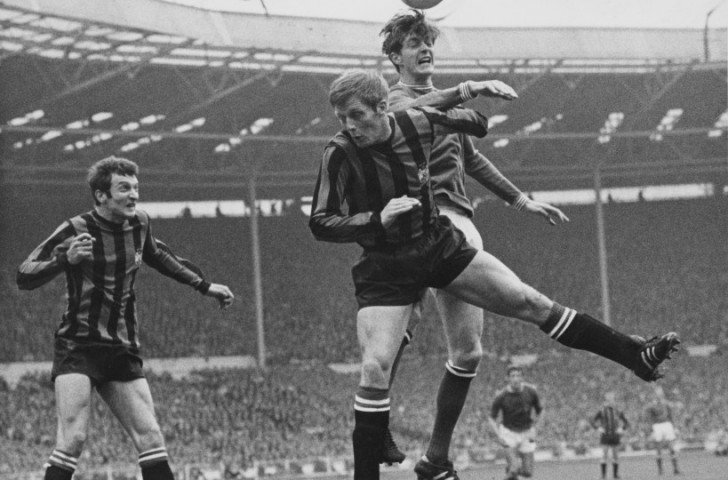 Neil Young, who scored the only goal of the 1969 FA Cup final for Manchester City against Leicester City, looks on as team-mate Alan Oakes challenges Allan Clarke for a header in classic red and black vertical stripes ©Getty Images