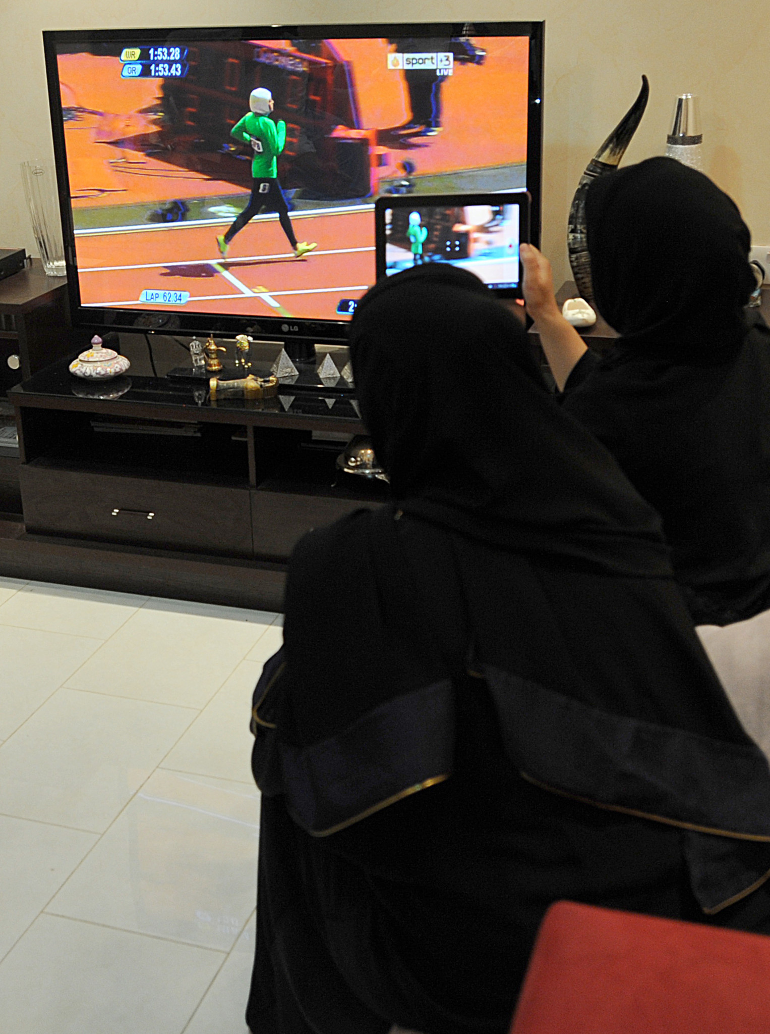 
Saudi women sit in a house in Riyadh watching and filming, via a tablet, Saudi Arabia’s Sarah Attar competing in the women’s 800m heats at the London 2012 Olympics ©Getty Images
