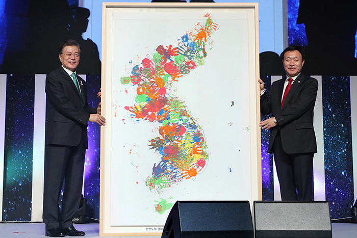 Moon Jae-in, left, receives a map of the Korean Peninsula painted by children from a Korean language school in Germany from Choi Young-keun, President of the Korean Community of Wiesbaden ©Korean Government