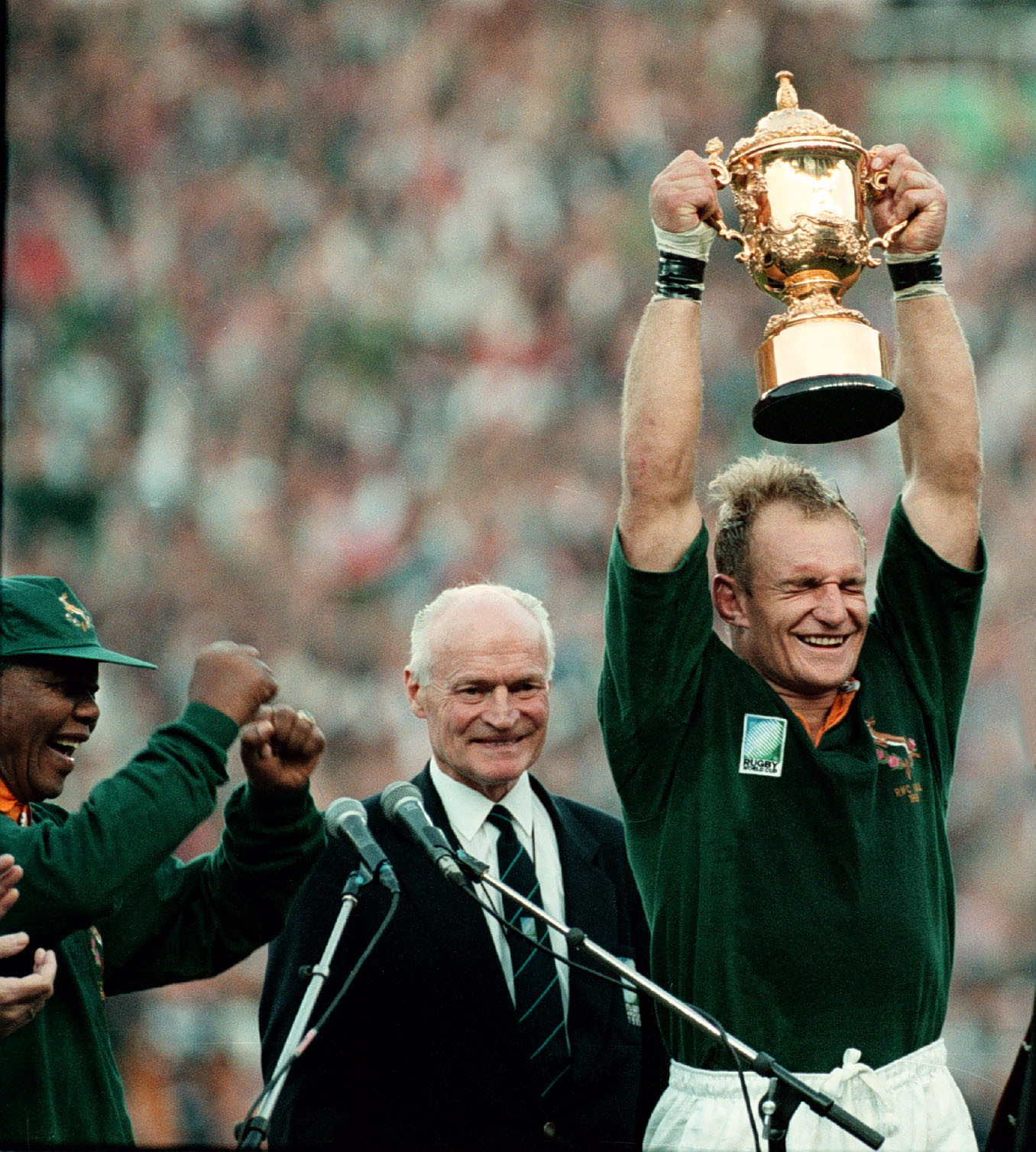 South Africa captain Francois Pienaar holds the 1995 World Cup aloft after defeating the New Zealand as President Nelson Mandela dances in joy ©Getty Images