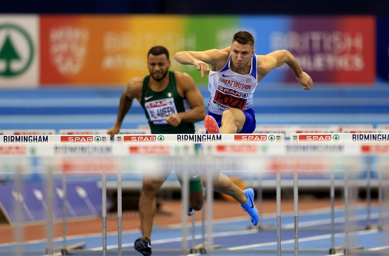 Britain's European indoor 60m hurdles champion Andy Pozzi in action at Arena Birmingham against a backdrop highlighting British Athletics's backing for the Stonewall Rainbow Laces initiative ©British Athletics